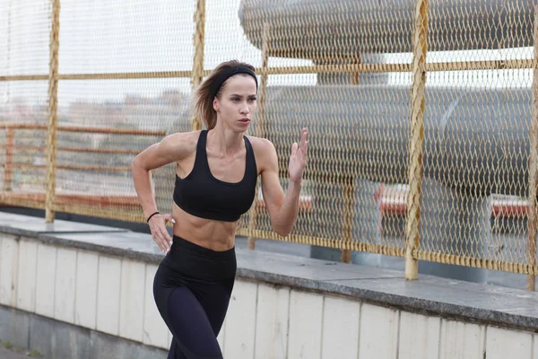 young slim sportswoman jogging outdoor in industrial zone of city, close up