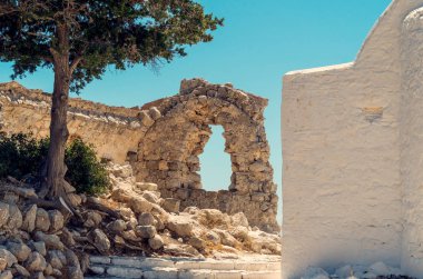 Rodos'taki bir ortodoks kilisesinin Monolithos kalesi, köknar ağacı ve beyaz duvarı kalıntıları, Yunanistan.