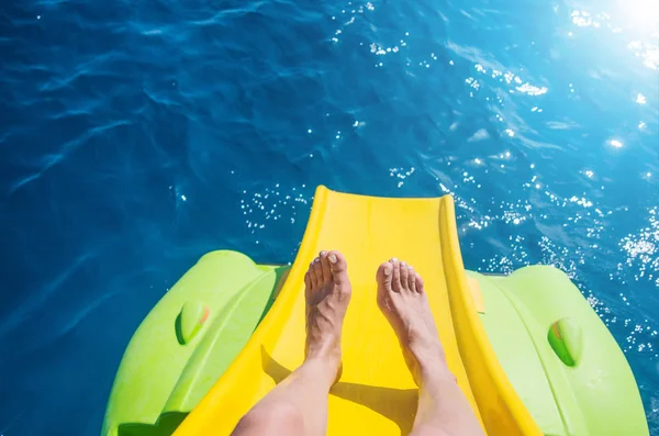 Female toes riding a water slidey on a pedal boat in the sea.