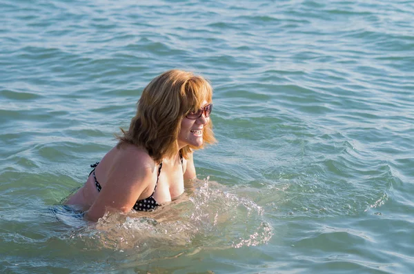 Güzel yaşlı kadın denizde banyo emeklilik zevk. Bir tatil gezisi sırasında gülen mutlu bir kadın