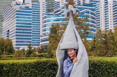 Taştan yapılmış ulusal Kazak kadın kostümünü deneyen bir Kazak kız. Nur-Sultan'ın merkezinde bir park