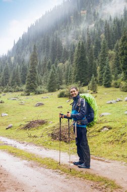 Bir dağ yolunda gülümseyen yürüyüş direkleri ile adam