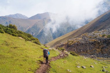 Bir dağ yolu boyunca yürüyen isimsiz adam