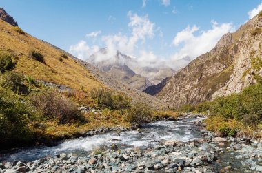 Mavi gökyüzünün altında dağ tepe, nehir ve çimen