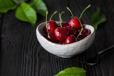 Tahta bir masada taze kirazlı kase.