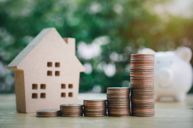 Kamu parkının arka planında ev modeli olan para yığını grafiği. Tasarruf ve yatırım kavramı.