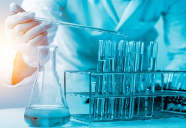 Bilim adamlarının el ele tutuştuğu pipette deney tüpü ve bilimsel deneylerin içine kimyasal sıvı içeren bir örnek bırakıyor., 