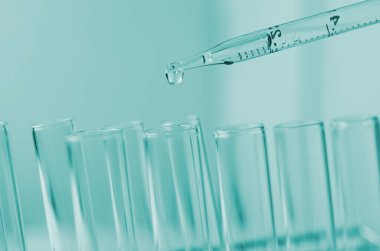 Pipette 'in deney tüpüne ve bilimsel deneylere bir numune bırakması, kimyasal sıvı içeren laboratuvar bardakları.