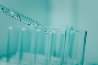 Pipette 'in deney tüpüne ve bilimsel deneylere bir numune bırakması, kimyasal sıvı içeren laboratuvar bardakları.