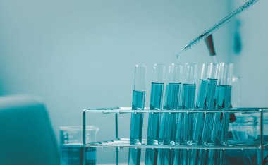 Pipette 'in deney tüpüne ve bilimsel deneylere bir numune bırakması, kimyasal sıvı içeren laboratuvar bardakları., 