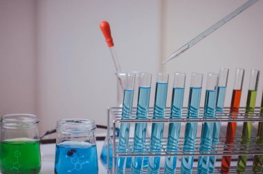 Pipette 'in deney tüpüne ve bilimsel deneylere bir numune bırakması, kimyasal sıvı içeren laboratuvar bardakları., 