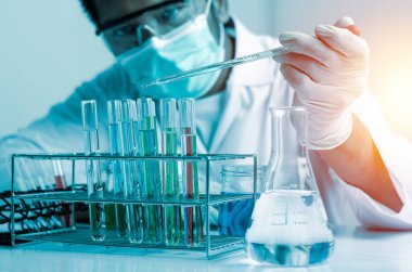 Bilim adamlarının el ele tutuştuğu pipette deney tüpü ve bilimsel deneylerin içine kimyasal sıvı içeren bir örnek bırakıyor., 