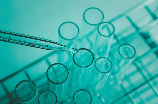 Pipette 'in deney tüpüne ve bilimsel deneylere bir numune bırakması, kimyasal sıvı içeren laboratuvar bardakları.