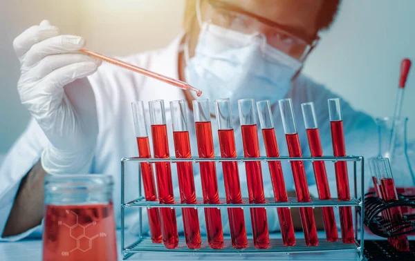 Bilim adamlarının el ele tutuştuğu pipette deney tüpü ve bilimsel deneylerin içine kimyasal sıvı içeren bir örnek bırakıyor., 