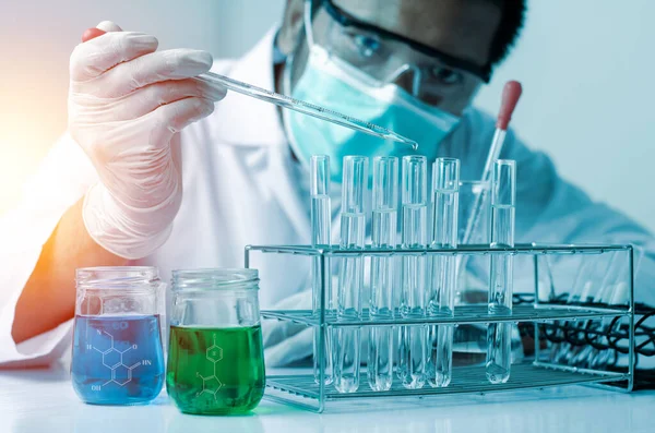 Bilim adamlarının el ele tutuştuğu pipette deney tüpü ve bilimsel deneylerin içine kimyasal sıvı içeren bir örnek bırakıyor., 