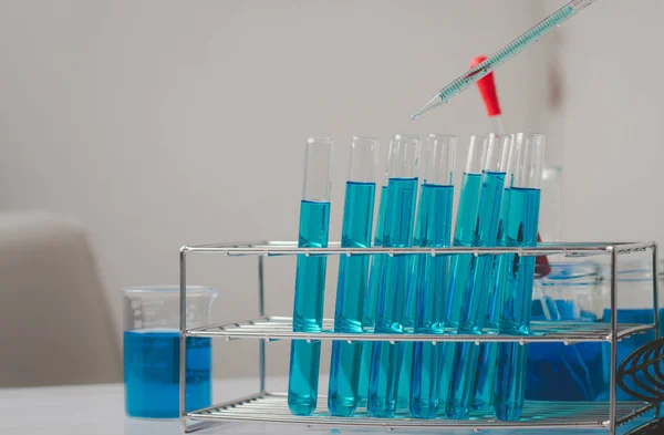 Pipette 'in deney tüpüne ve bilimsel deneylere bir numune bırakması, kimyasal sıvı içeren laboratuvar bardakları., 