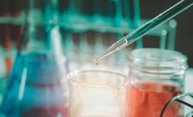 Bilim adamlarının el ele tutuştuğu pipette deney tüpü ve bilimsel deneylerin içine kimyasal sıvı içeren bir örnek bırakıyor., 