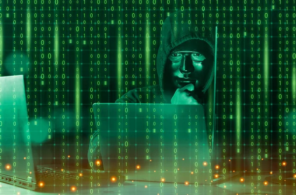 Hacker ve kötü amaçlı yazılım konsepti. Tehlikeli Kapüşonlu hacker ikili kod dijital arayüzü olan dizüstü bilgisayar kullanıyor..