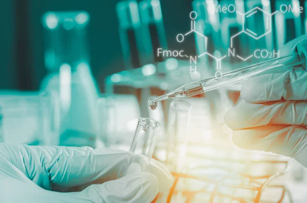 Bilim adamlarının el ele tutuştuğu pipette deney tüpü ve bilimsel deneylerin içine kimyasal sıvı içeren bir örnek bırakıyor., 