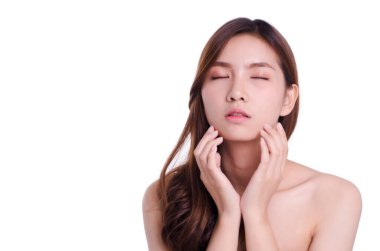 Asyalı genç ve güzel bir kadın gülümseyip yüzüne dokunuyor, beyaz arka planda soyutlanmış. Doğal makyaj, SPA terapisi, cilt bakımı, kozmetoloji ve estetik cerrahi konsepti