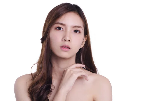 Asyalı genç, güzel bir kadın gülümseyip omzuna dokunuyor, beyaz arka planda soyutlanmış. Doğal makyaj, SPA terapisi, cilt bakımı, kozmetoloji ve plastik cerrahi konsepti.