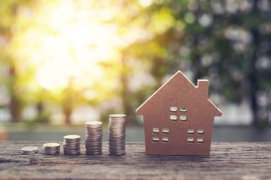 Para yığını basamakları parktaki ahşap masanın üzerinde büyüyen model ev. Finansal tasarruf. Eski model renk tonu