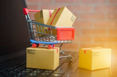 Dizüstü bilgisayarda, klavyede, tuğla zeminde bir sürü kutu var. Fikirler çevrimiçi alışveriş, tüketicilerin İnternet üzerinden doğrudan mal satın almalarına olanak sağlayan bir elektronik ticaret biçimidir..