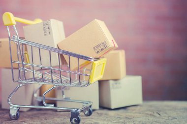 Alış veriş arabasındaki karton kutular ahşap masa, e-ticaret veya elektronik ticaret internet üzerinden mal veya hizmet satın alma veya satma işlemidir..