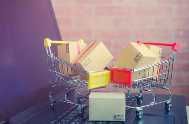 Laptop klavyesindeki alışveriş arabasındaki karton kutular, e-ticaret veya elektronik ticaret internet üzerinden mal veya hizmet satın alma veya satma işlemidir..