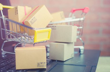 Laptop klavyesindeki alışveriş arabasındaki karton kutular, e-ticaret veya elektronik ticaret internet üzerinden mal veya hizmet satın alma veya satma işlemidir..