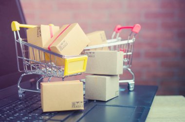 Laptop klavyesindeki alışveriş arabasındaki karton kutular, e-ticaret veya elektronik ticaret internet üzerinden mal veya hizmet satın alma veya satma işlemidir..