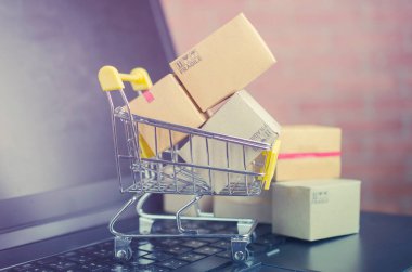Laptop klavyesindeki alışveriş arabasındaki karton kutular, e-ticaret veya elektronik ticaret internet üzerinden mal veya hizmet satın alma veya satma işlemidir..