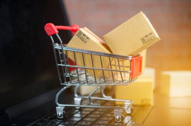 Dizüstü bilgisayarda, klavyede, tuğla zeminde bir sürü kutu var. Fikirler çevrimiçi alışveriş, tüketicilerin İnternet üzerinden doğrudan mal satın almalarına olanak sağlayan bir elektronik ticaret biçimidir..