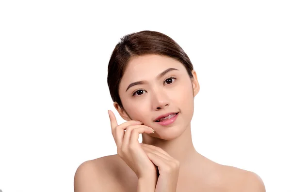 Kısa saçlı, Asyalı güzel bir kadın gülümseyip yüzüne dokunuyor, beyaz arka planda soyutlanmış. Doğal makyaj, SPA terapisi, cilt bakımı, kozmetoloji ve estetik cerrahi konsepti