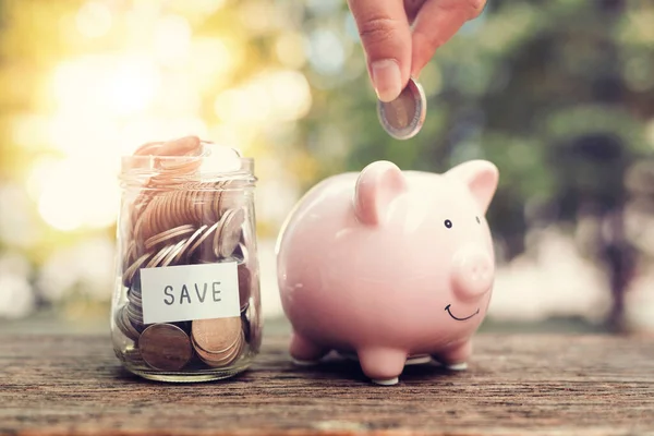 Mãos Mulher Segurar Moedas Colocando Moeda Piggy Bank Mesa Madeira — Fotografia de Stock