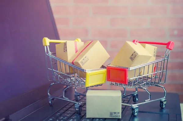 Laptop klavyesindeki alışveriş arabasındaki karton kutular, e-ticaret veya elektronik ticaret internet üzerinden mal veya hizmet satın alma veya satma işlemidir..