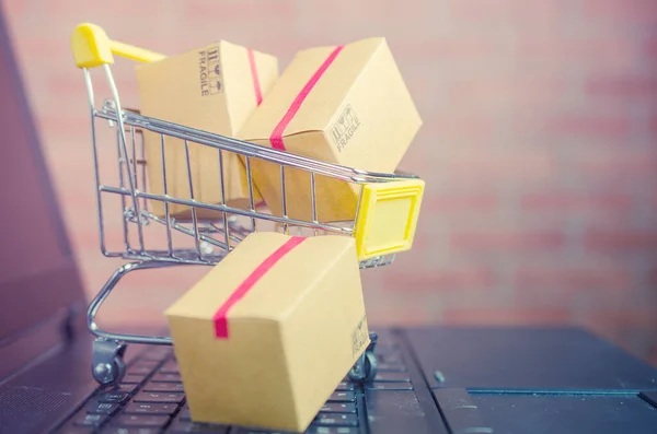Laptop klavyesindeki alışveriş arabasındaki karton kutular, e-ticaret veya elektronik ticaret internet üzerinden mal veya hizmet satın alma veya satma işlemidir..