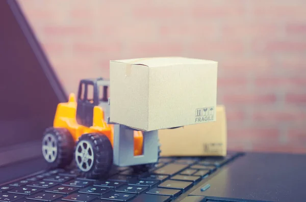 Forklift truck with boxes on a laptop keyboard,e-commerce or electronic commerce is a transaction of buying or selling goods or services online over the internet.