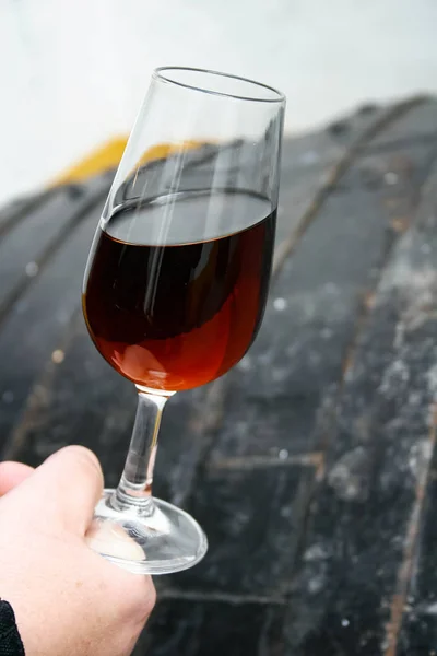 Catavino, cup for wine, with Sherry cream on hand with barrel background