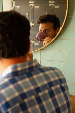 Kahve içen genç adamın portresi aynaya yansıdı