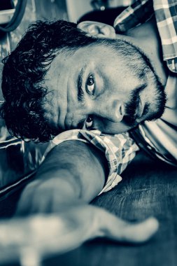 Kafeterya masasına yaslanan genç adam ciddi görünüyor