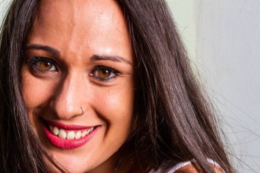 Stüdyo aydınlatma portresi ifade eden gözlerle gülümseyen genç bir kadın.