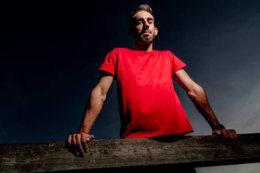 Sporcu gün batımında kumsalın yanındaki güverteye yerleştirilmiş makineler üzerinde egzersiz yapıyor.