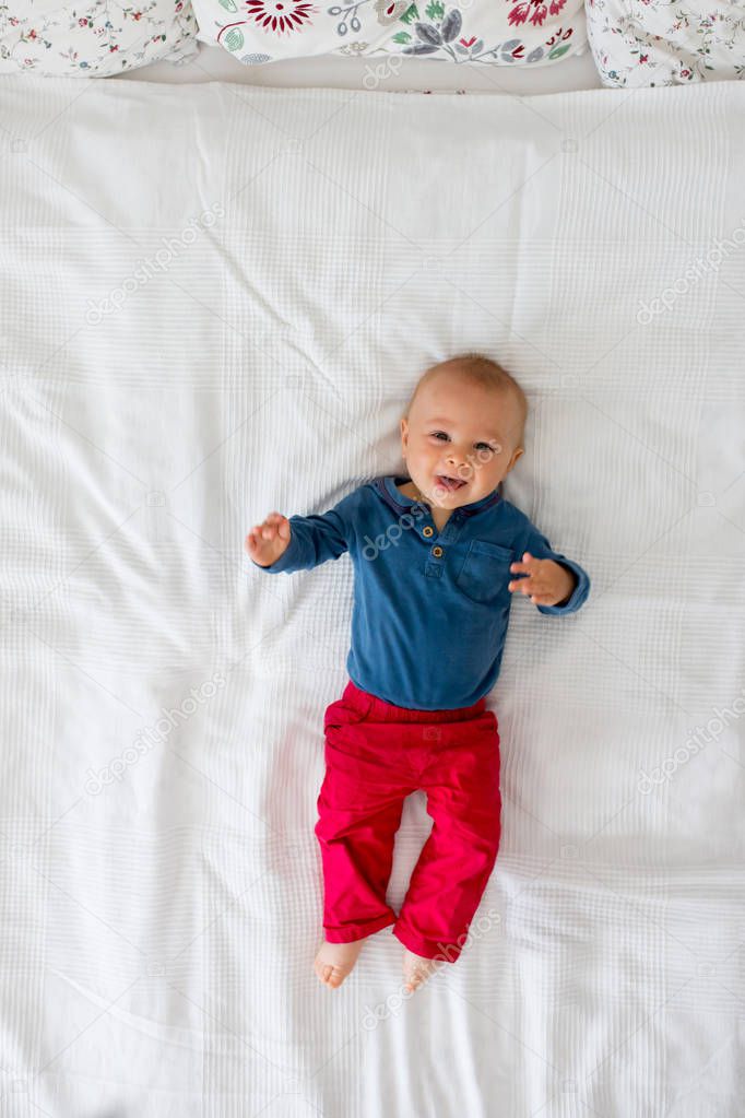 Mother and toddler baby boy, lying in bed, hugging with love, high angle shot, from above. Happy family concep