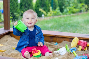 Bir sandpit açık havada oyuncakları ile oynarken küçük oğlu,