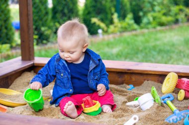 Bir sandpit açık havada oyuncakları ile oynarken küçük oğlu,