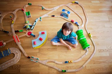 Tatlı okul öncesi çocuk, ahşap demiryolu ve evde, trenler oynayan çocuk, görünümü top
