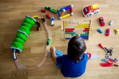 Okul öncesi çocuk abaküs ve diğer oyuncaklar ile oynama, ahşap katta oturan, üstten görüntülemek. Eğitim kavramı