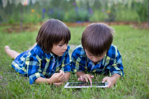 Dos Niños Edad Preescolar Hermanos Jugando Tableta Acostados Hierba Jardín —  Fotos de Stock