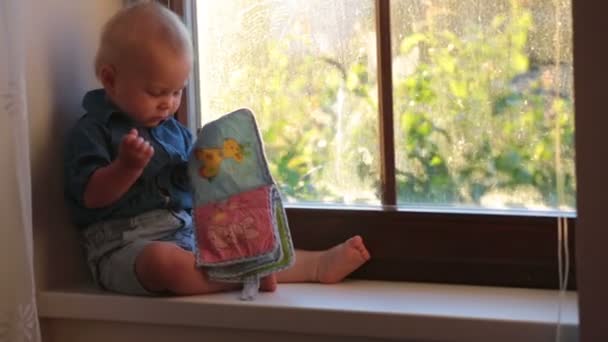 Мальчик Симпатичный Ребенок Сидящий Окна Закате Счастливо Играющий Детской Книжкой — стоковое видео